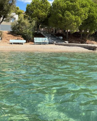 a beach with a bench and some water and trees at Marina Helios Home in Áyios Yeóryios