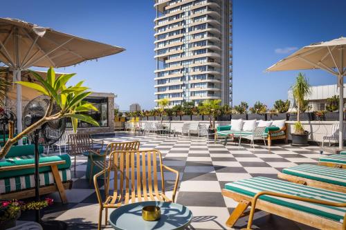 eine Terrasse mit Stühlen und Tischen und ein Gebäude in der Unterkunft Pixel Hotel - Rooftop & Spa in Tel Aviv