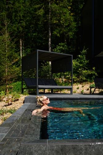 a woman in a swimming pool next to a bench at Hotel Fischerwirt Natur WaldSPA in Faistenau