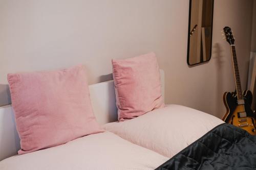 a bed with two pink pillows and a guitar at Anubis relaxed&stay in Hamburg