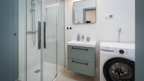 a bathroom with a sink and a washing machine at Apartament A03 Karwica Zapach Lasu in Karwica