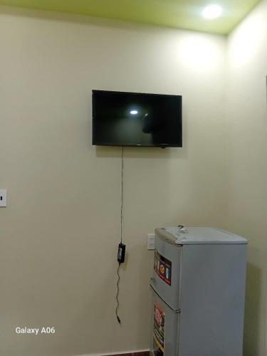 a flat screen tv on the wall above a refrigerator at HOTEL MOTeL ĐỒNG KHỞI in Ben Tre