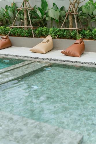a pool with pillows sitting next to a swimming pool at PAAK Hotel Suvarnabhumi in Lat Krabang