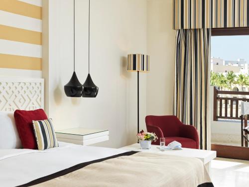 a bedroom with a bed and a red chair at Juweira Boutique Hotel Adult only in Salalah