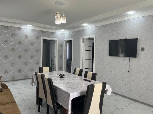 ein Esszimmer mit einem Tisch und einem Fernseher an der Wand in der Unterkunft AllGreen House in Qəbələ