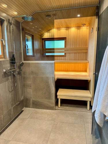 a bathroom with a shower and a bench in it at Aurora Arctic Riverside Villa in Rovaniemi