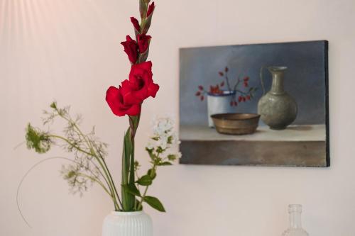 a vase with red flowers in it next to a painting at Stilvolles Ambiente im grünen Hamburg! in Hamburg