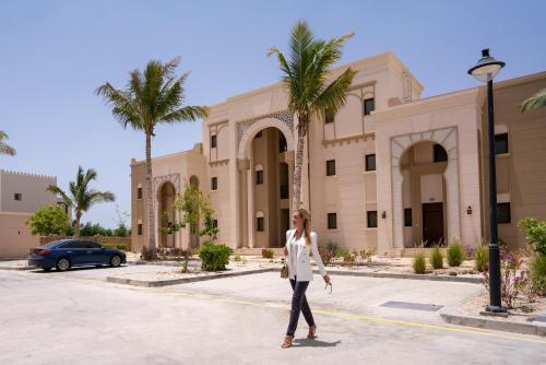 a woman is standing in front of a building at Juweira Boutique Hotel Adult only in Salalah