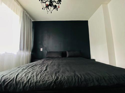 a bedroom with a bed with a black wall at Black Apartment at Blossom Hill in Tallinn