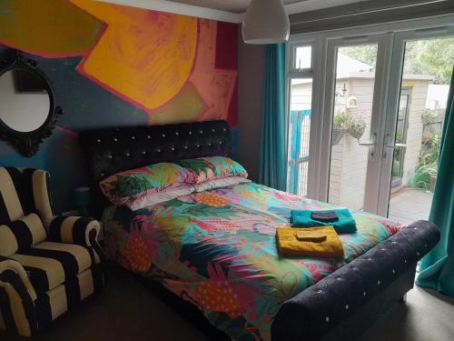a bedroom with a bed with a comforter and a chair at Sailaway in Carbis Bay