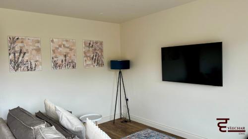 a living room with a couch and a flat screen tv at Spacious 4BR Home New Forest-Parking & Pet Friendly in Lymington