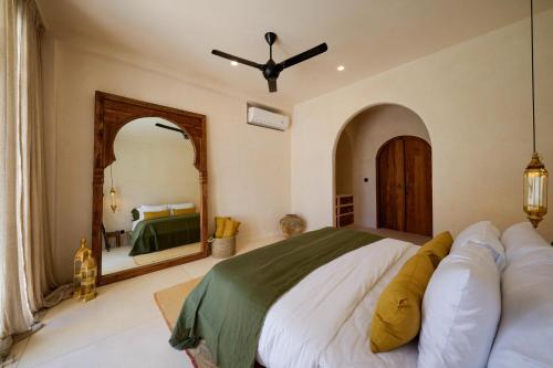 Un dormitorio con una cama grande y un espejo grande. en Kalesma Uluwatu Luxury 6BR Side by side, en Uluwatu