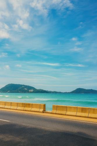 a road with a view of the ocean and a beach at Orchid Hotel and Spa Kalim Bay in Patong Beach