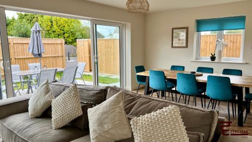 a living room with a couch and a table and chairs at Spacious 4BR Home New Forest-Parking & Pet Friendly in Lymington