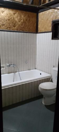 a bathroom with a tub and a toilet and a sink at Villa bungalow restoApung in Kubupenlokan