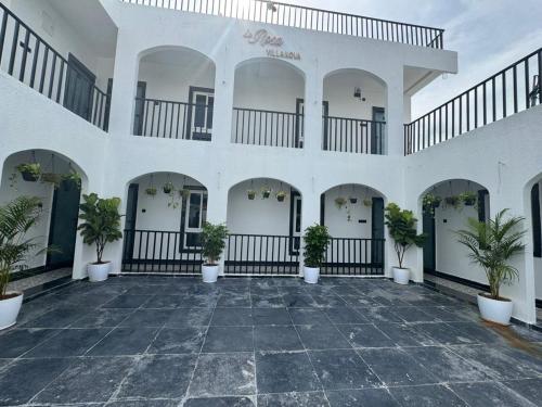 a large white building with potted plants in the courtyard at LaRosa VillaNova in Hyderabad