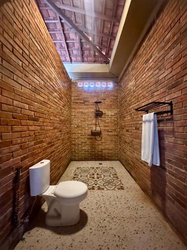 a bathroom with a toilet and a brick wall at Pulojava Resort in Karimunjawa