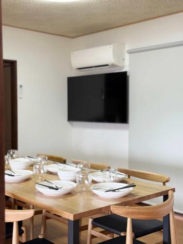 a wooden table with chairs and plates and a television at Ryu no Torimichi - Hilltop House Scenic Stay with City Views in Onomichi