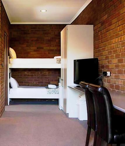 a room with a desk with a computer and a television at Fountain Court Motor Inn Albury in Albury