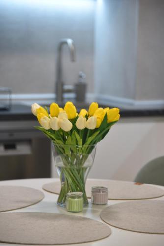 a vase of yellow and white flowers on a table at Urban Elegance Studio & SPA in Niš