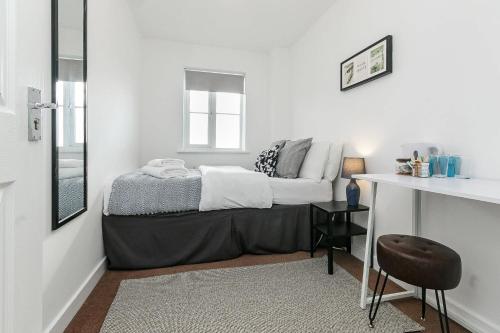 a bedroom with a bed and a table with a chair at Comfortable 4 Bed Modern Townhouse with Parking in Long Eaton