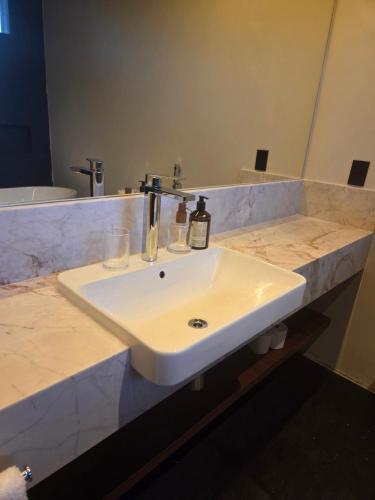 Un lavabo blanco en un baño con espejo. en Vinicola Spirito, en Espírito Santo do Pinhal