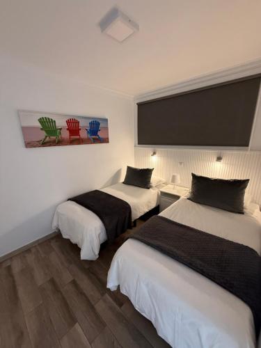two beds in a hotel room with a large screen at Solarena - Sol44 in Maspalomas