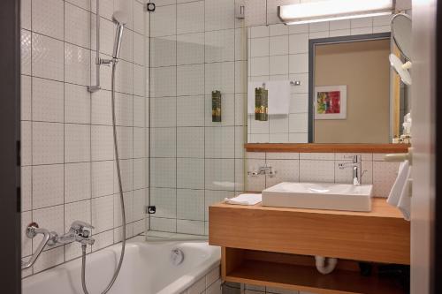 a bathroom with a tub and a sink and a shower at Hotel Gasthof Krönele in Lustenau