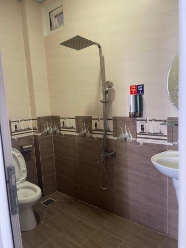 a bathroom with a shower and a toilet and a sink at KHÁCH SẠN MlLAN in Dĩ An