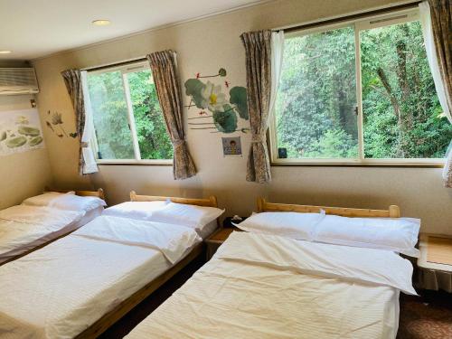 two beds in a room with two windows at 菜音天然温泉別荘 in Tsu