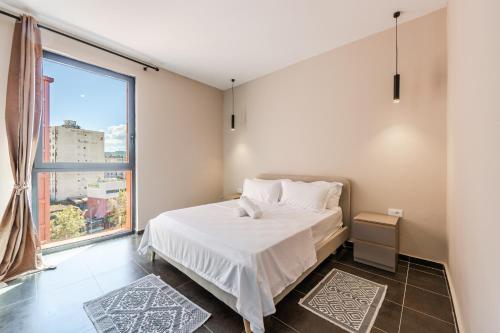 Un dormitorio con una cama y una ventana grande. en Galleria Roma Aparthotel, en Tirana
