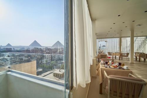 Habitación con mesa y ventana grande con vistas. en Merak Pyramids Hotel, en El Cairo