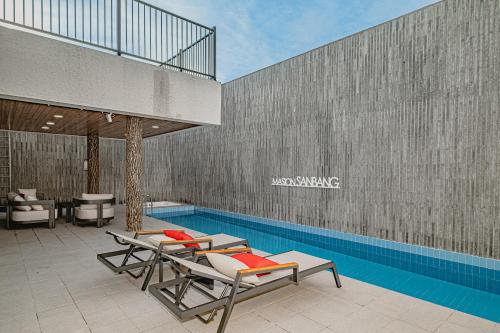 a swimming pool with two lounge chairs next to a building at Masion Sanbang Jeju in Seogwipo