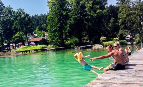 a group of people jumping into a body of water at VEGAN Pension & Restaurant in Sankt Kanzian