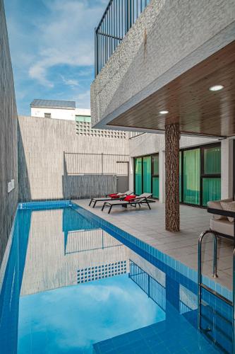 a swimming pool with a patio and a building at Masion Sanbang Jeju in Seogwipo