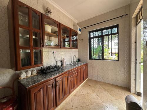 een keuken met houten kasten, een wastafel en een raam bij Apartment 72 in Moshi