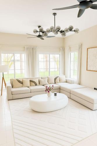 a white living room with a white couch and a table at Family Villa, Sleeps up to 9 in JVT and Large garden in Dubai