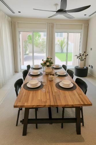 a wooden table in a living room with chairs at Family Villa, Sleeps up to 9 in JVT and Large garden in Dubai