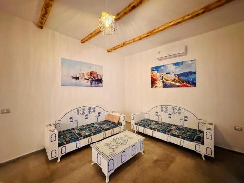 a room with three beds and a painting on the wall at Dar Inès in Al Maqārisah