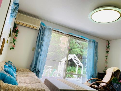 a bedroom with a bed and a window with blue curtains at 菜音天然温泉別荘 in Tsu