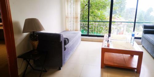 a living room with a couch and a lamp and a window at Mezbaan guest house in Nathia Gali
