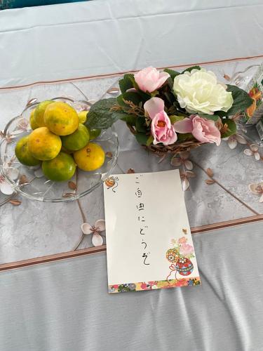 a table with a plate of fruit and a sign at 菜音天然温泉別荘 in Tsu
