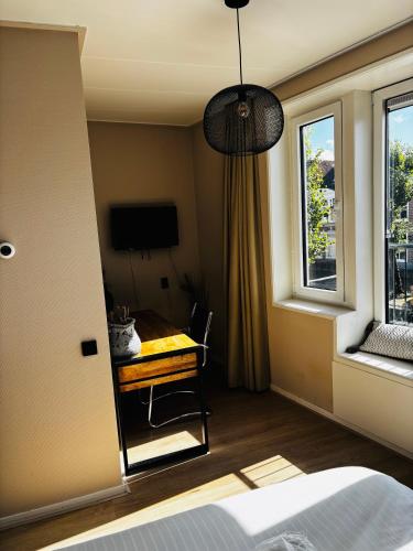 a bedroom with a bed and a desk and a window at Stadshotel DE ACADEMIE in Franeker