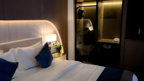 a bedroom with a white bed with blue pillows at Grand Day Hotel Boutique in Al Hofuf