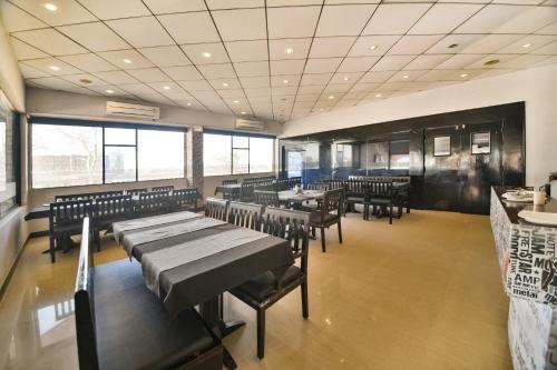 a dining room with tables and chairs and windows at Capital O Amit Palace in Bhilwara