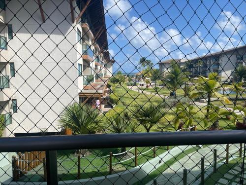 a chain link fence with a view of a building at Refeições inclusa - Polinesia Resort - Porto de Galinhas - Apartamentos com somente 1 opção de Térreo com Piscina Privativa - Acesso ao Hotel Samoa in Porto De Galinhas