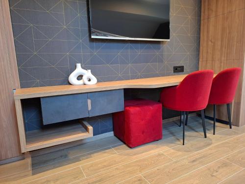 a desk with two red chairs and a television on a wall at Tara Escape Apartment - Kaluđerske Bare 