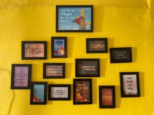 a wall with a bunch of pictures on a yellow wall at New View Homestay in Veer Savarkar International Airport