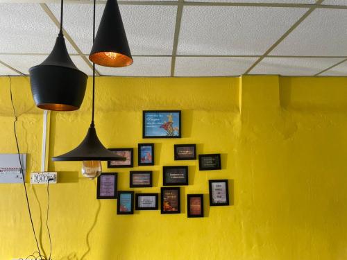 a yellow wall with a bunch of pictures on it at New View Homestay in Veer Savarkar International Airport