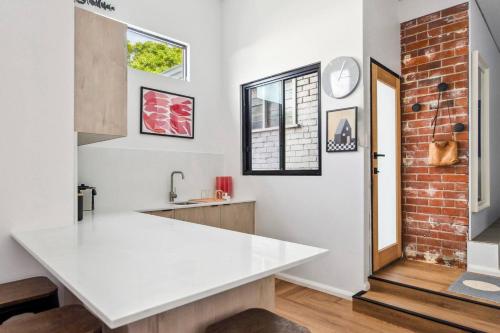 a kitchen with a white counter and a brick wall at Fremantle Swan River Studio in East Fremantle